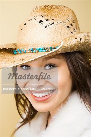 Young adult Caucasian woman wearing cowboy hat smiling at viewer.