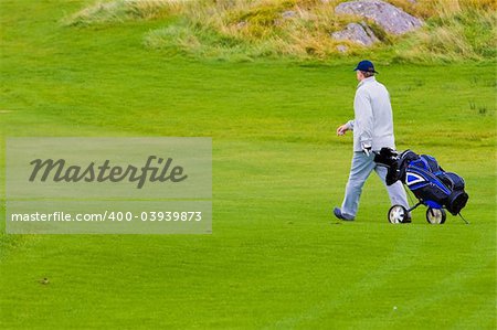 A golfer with bag, walking along the grass