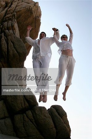 Couple jumping together from the top of the mountain