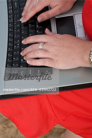 Close up of a female in red dress typing on a laptop