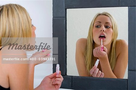 A beautiful young blonde woman putting on her make-up and getting ready to go out