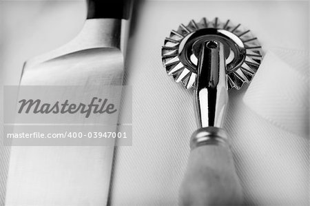 Cook's knife and ravioli wheel cutter on a chef's uniform. Original colour file converted to greyscale via L/ab, then RGB with levels and tonal adjustment.