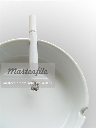 close photo of cigarette and ashtray on white background