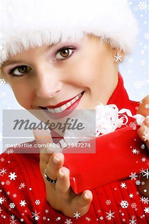 winter portrait of a smiling woman with a gift in her hands and snowflakes