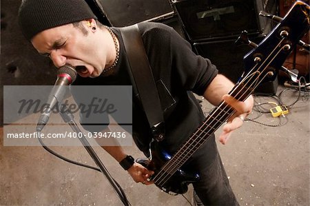 Bassist playing and screaming into a microphone.