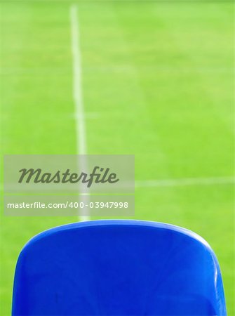 Blue seat and green grass on a soccer stadium