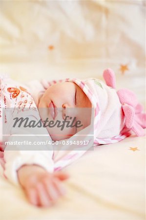Lying sleeping baby with small teddy bear on bright background