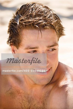 Head and shoulder portrait of handsome man on beach.