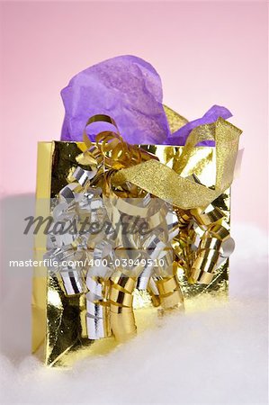 A small gold metallic gift bag with ribbons