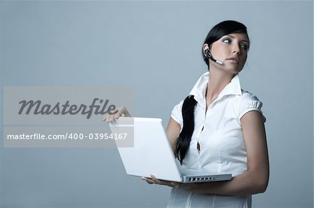 Beautiful brunette business woman with wireless headset and laptop computer isolated on clear background
