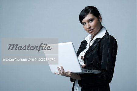 Beautiful and sexy brunette business woman with laptop computer. She is isolated on clear background