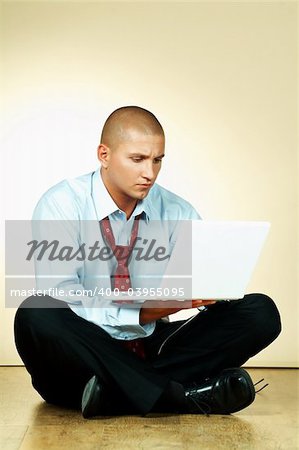 A businessman using laptop computer and sitting on wooden floor