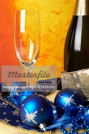 Christmas decoration with champagne bottle and empty glass over colour background. Shallow DOF