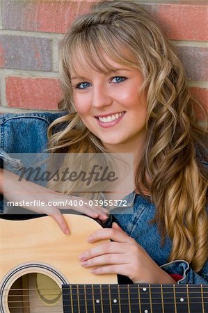 A pretty young woman resting on an acoustic guitar