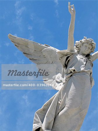 detail of winged angel statue against blue sky