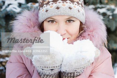 Beautiful girl in hat and mittens holding some snow
