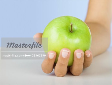 Close-up of a female hand holding a green apple