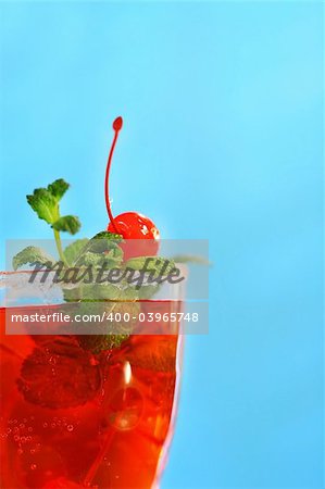 Red tropical drink with mint and cherries against a blue sky
