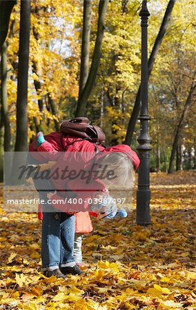 Happy family (mother with small children) in golden autumn city park