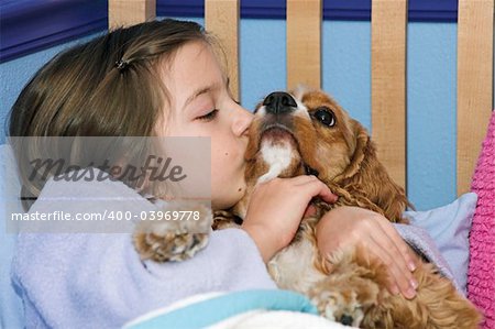 a little girl giving her puppy a kiss goodnight