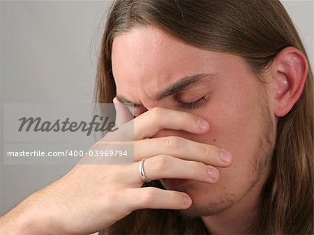 a teenaged boy with his head in his hands, very depressed or with a headache