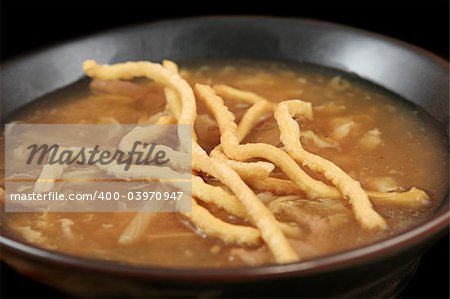 A closeup of Szechuan Chinese hot & sour soup with crunchy fried noodles. (focus on noodles in center of bowl)
