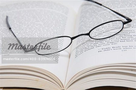 A pair of black framed reading glasses resing on a book.