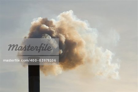 Fumes belch out of the top of an industrial chimney