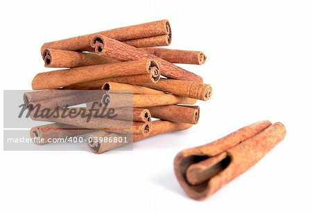 A house made from cinnamon sticks and a single stick nearby with focus on the house shot on a white background