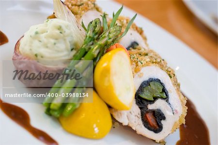 Breaded chicken slices stuffed with sweet peppers and served with asparagus and vegetables