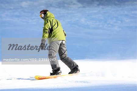 Man with snowboard going down a ski slope. Face not recognisable.