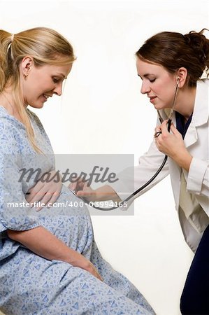 Pregnant blond woman being examined by a female doctor holding a stethoscope on the stomach