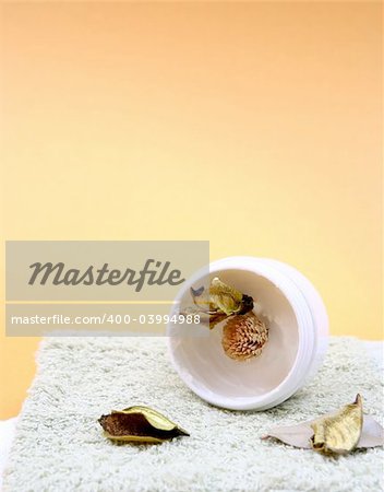 Spa essentials (cream, white towel and flowers) isolated on yellow