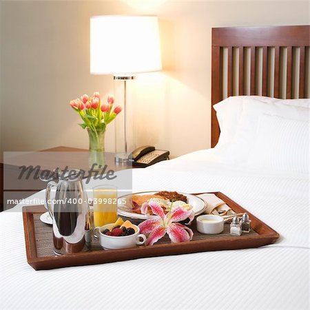 Breakfast tray laying on white bed in upscale hotel.