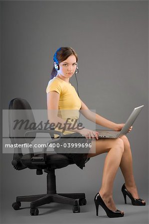 an office worker sitting down with the laptop on her legs and earphone
