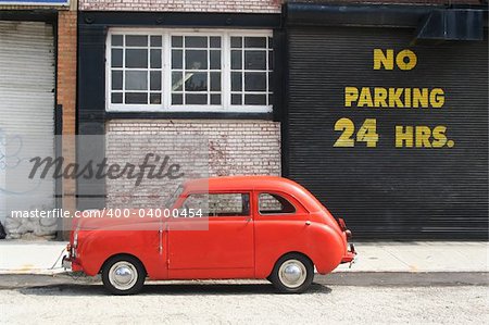 An old vintage car next to a no parking sign.