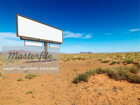 Blank billboard in middle of desert landscape with distant mountains.