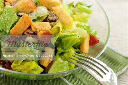 Fresh caesar salad with croutons and bacon bits served in a glass bowl