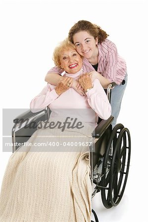 Senior woman in wheelchair gets hug from her teen granddaughter.  Isolated on white.