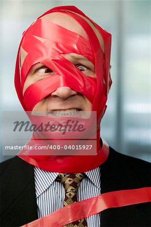 Cross-eyed businessman wrapped in red tape