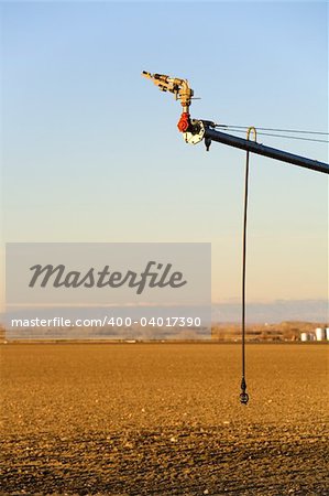 agriculture - modern automated irrigation system, closeup on end of arm with two sprinklers. Blue sky, late sun.