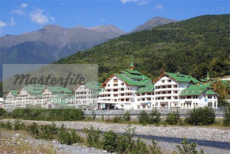 Long white house cwith green roof on the river bank in Krasnaya Polyana, Sochi, Russia