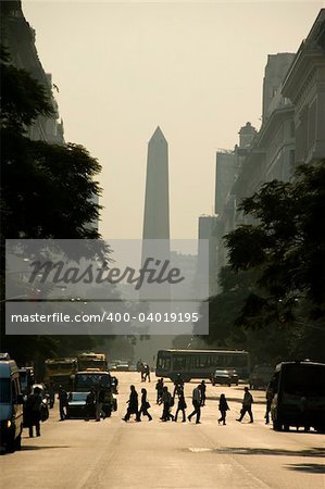 In the center of the Argentina capital city of Buenos Aires, with the obelisk in the background and silhouetted people crossing the street.