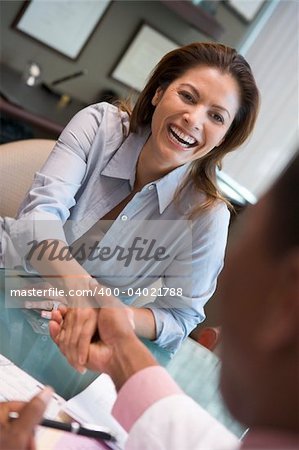 Woman sitting at desk shaking doctor's hand at IVF clinic