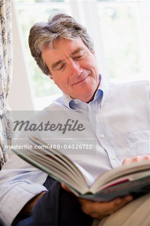 Man in living room reading book smiling