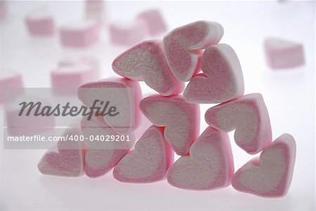 Heart shaped marshmallows in a pile with others floating in the background