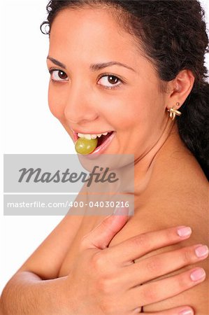 A smiling lady eats grape, standing on white background.