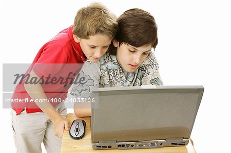 Two adorable brothers using the computer together.  Isolated on white.