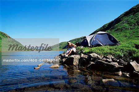 Young woman washing in lake next to camp