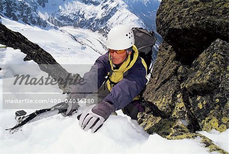 Mountaineer using an ice axe to climb a steep slope